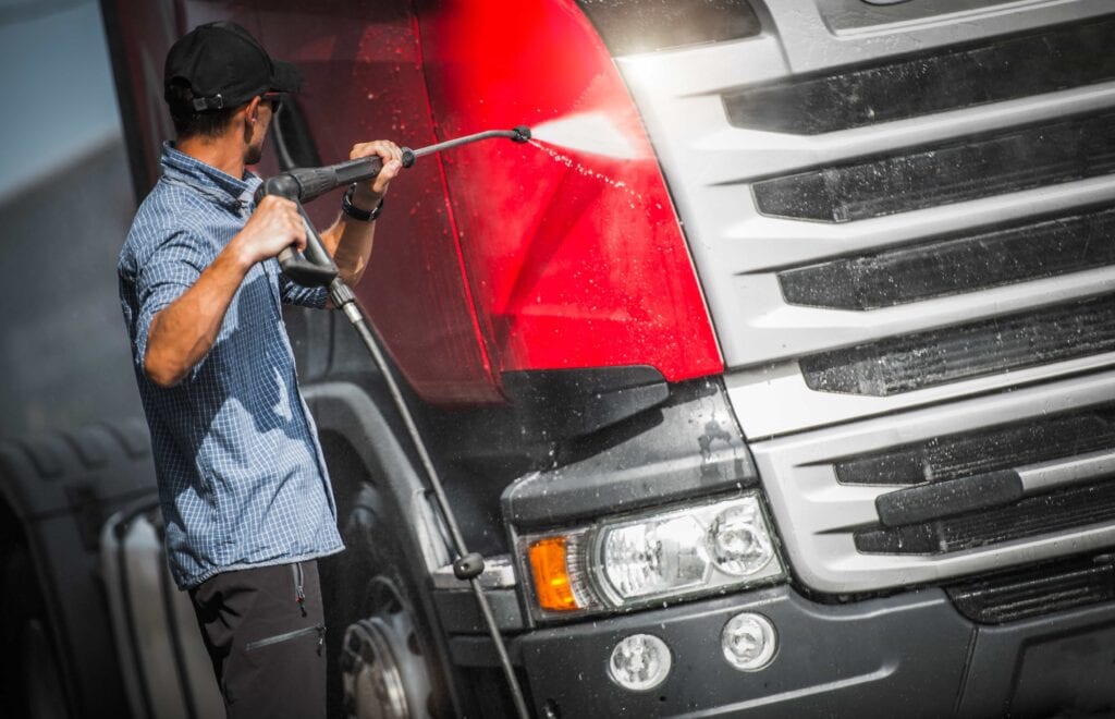 High-Pressure Cleaning of a Red Commercial Semi-Truck
