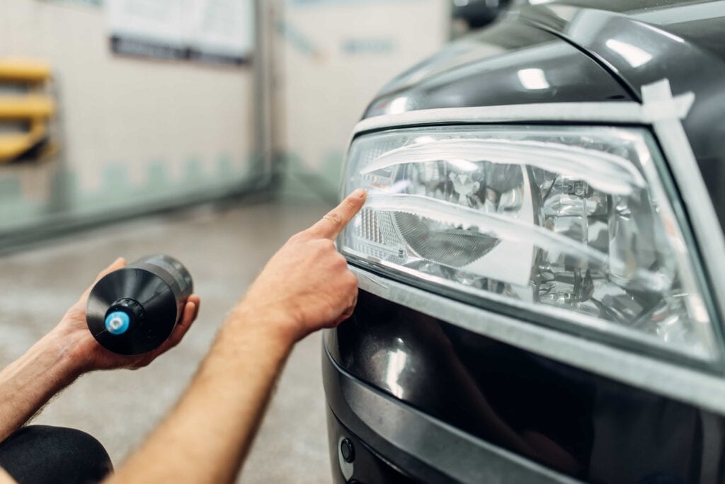 A professional headlight restoration service applying polishing compound to cloudy, oxidized car lights for a vehicle in Florida.
