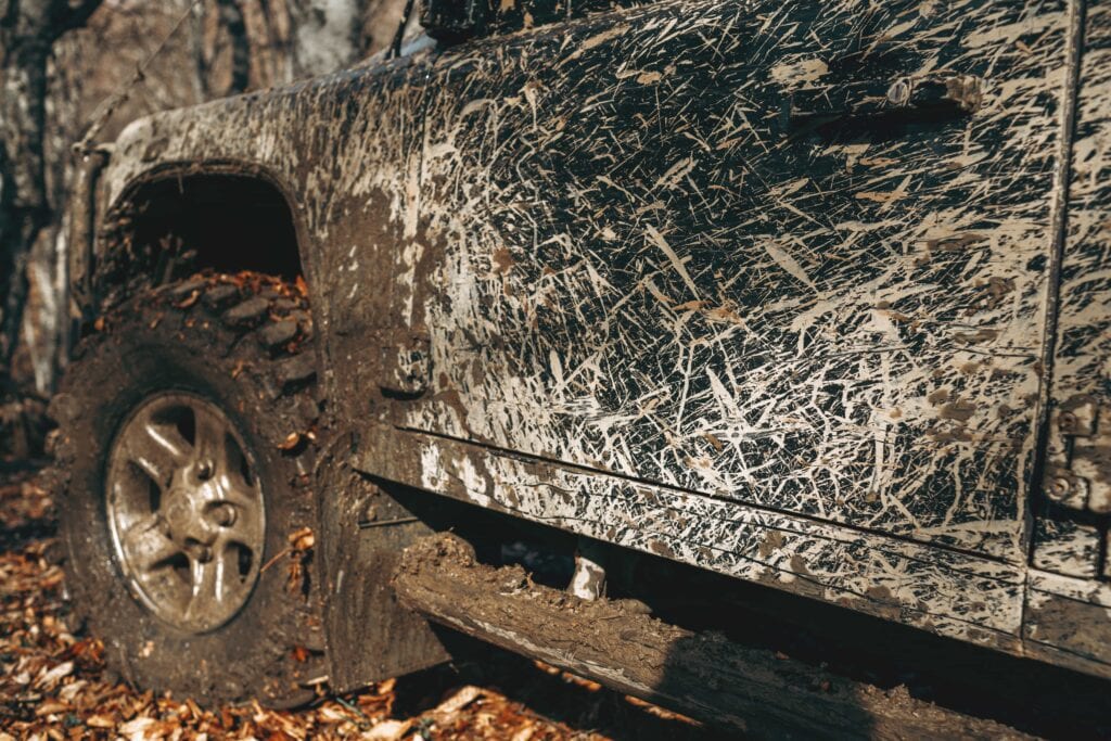 A mud-caked 4x4 off-road vehicle covered in thick trail debris requiring professional exterior detailing and decontamination services in Florida.