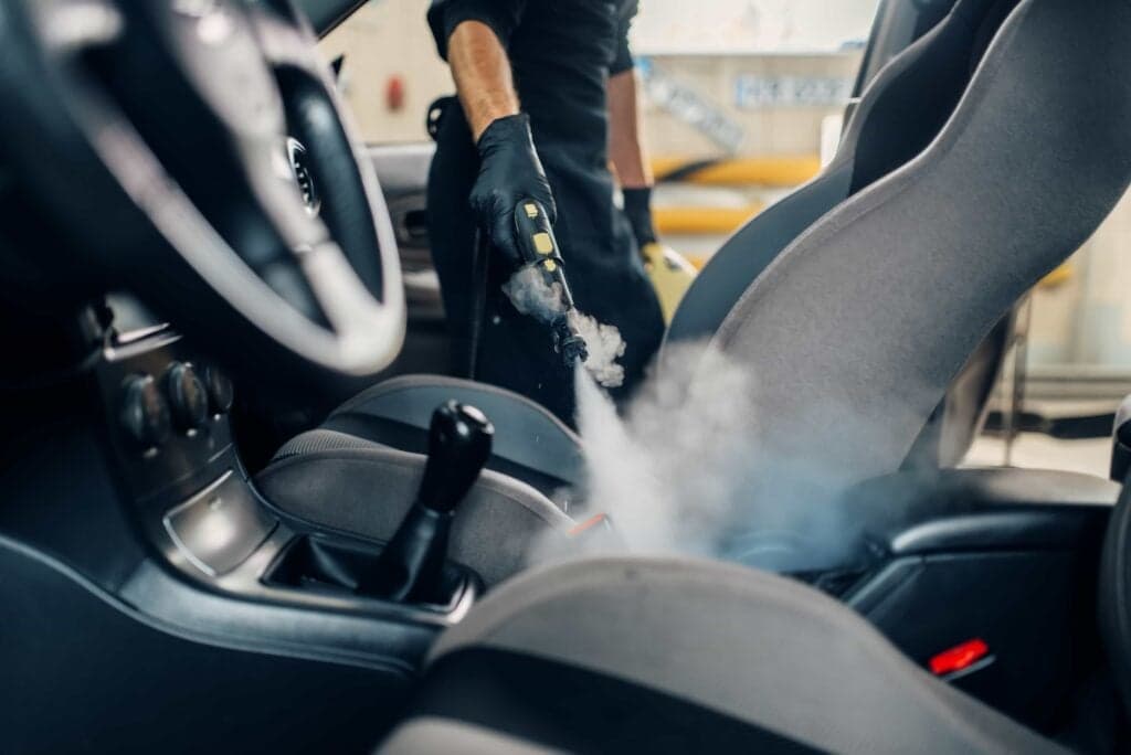 A professional detailing specialist performing deep interior car steam cleaning in Ocala, FL.