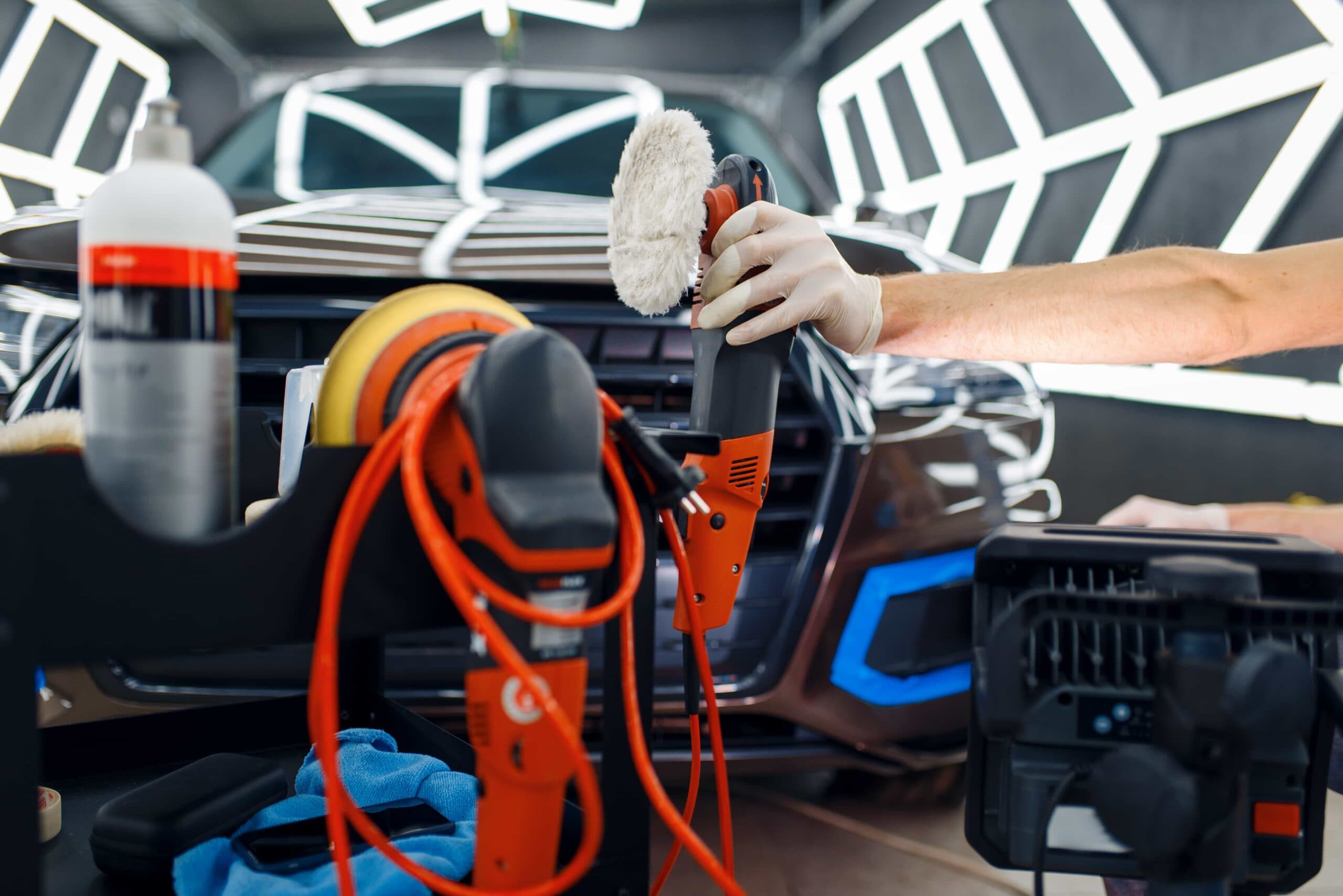 A technician performing professional car paint polishing in an auto detailing workshop in Ocala, FL.